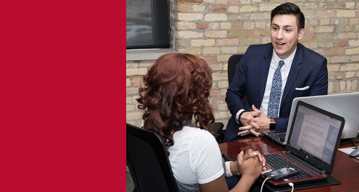 Business students talking at a conference table with a laptop