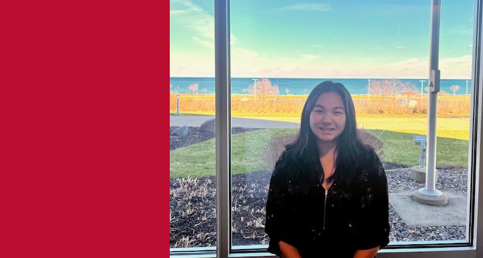 Gateway student Amy Brewer smiling in front of a window with a view of Lake Michigan in the background