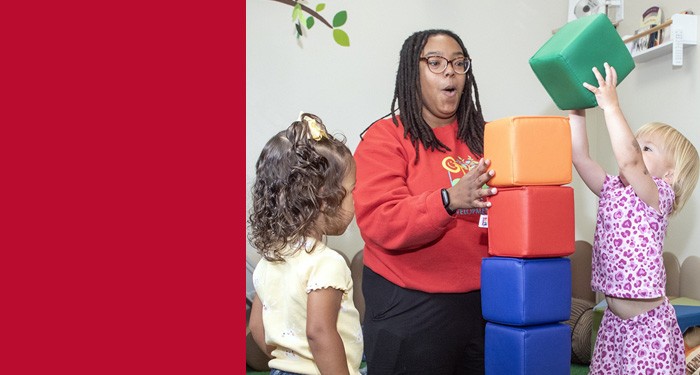Alishah Miller, Early Childhood Education Graduate, and young children play with large blocks
