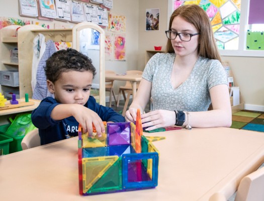 Early Childhood Education student works with a child at table with a colorful shape toy