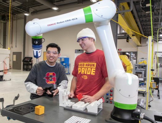 Two Gateway Advanced Manufacturing students operate a robotic arm