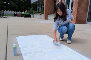 Gateway student using chalk spray paint and stencils around campus to bring awareness to National Voter Registration Day
