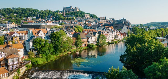 Aerial view of Marburg, Germany with stunning architecture, surrounded by lush greenery and a river valley.