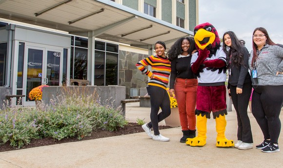Students with Gateway's Rudy the Red Hawk mascot in front of one of Racine Campus' buildings