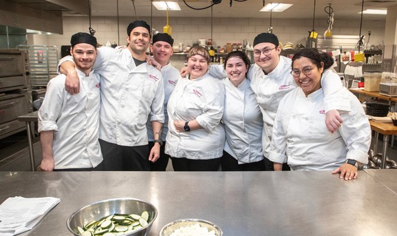 A group of culinary students smiling in the kitchen on the Racine Campus