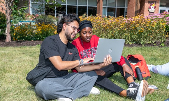 Two Gateway students in an outside common area on campus looking at a laptop