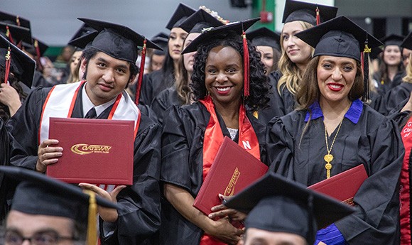 Group of Gateway graduates smiling in caps and gowns.