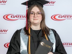 Karley Webb at commencement in cap and gown holding a commencement program