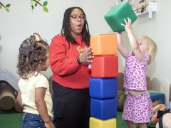 Alishah Miller interacts with two preschool-aged children in a classroom.
