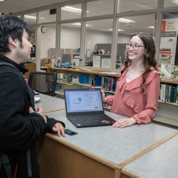 Carly Hawkins in a Gateway library smiling at another student