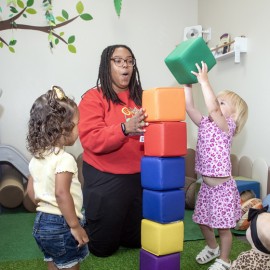 Alishah Miller interacts with two preschool-aged children in a classroom.
