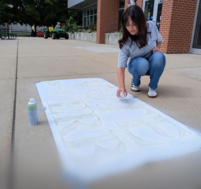 Gateway student using chalk spray paint and stencils around campus to bring awareness to National Voter Registration Day